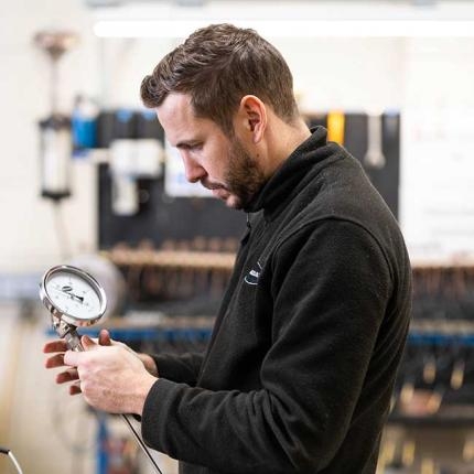 man inspecting a pressure guage
